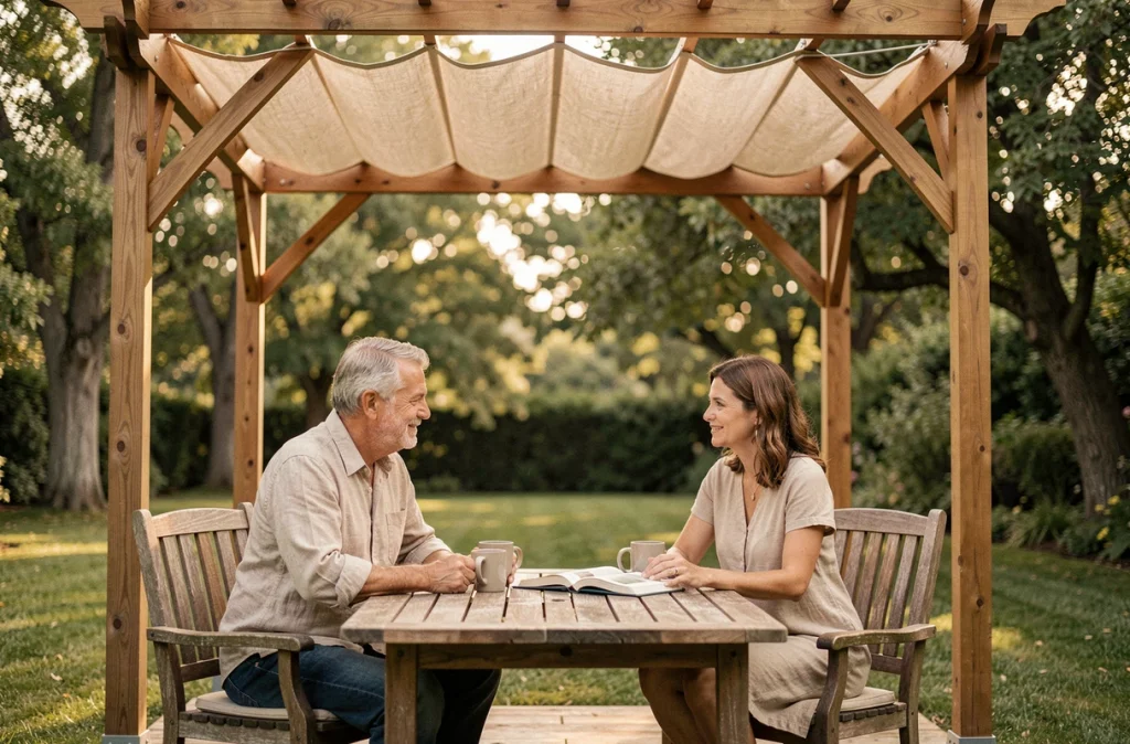 Couple profitant de leur pergola en bois avec voile d'ombrage dans le jardin en toute saison