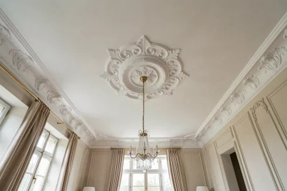 Plafond décoratif avec moulures en plâtre blanc et médaillon central dans un salon rénové au style classique français