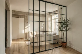Verrière intérieure en acier noir séparant un séjour et un couloir dans un appartement parisien moderne